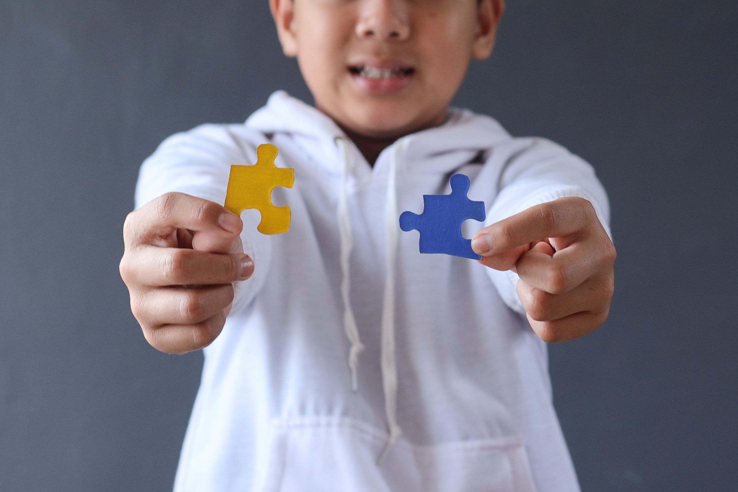 A child holding puzzle pieces, a representational image for autism awareness.