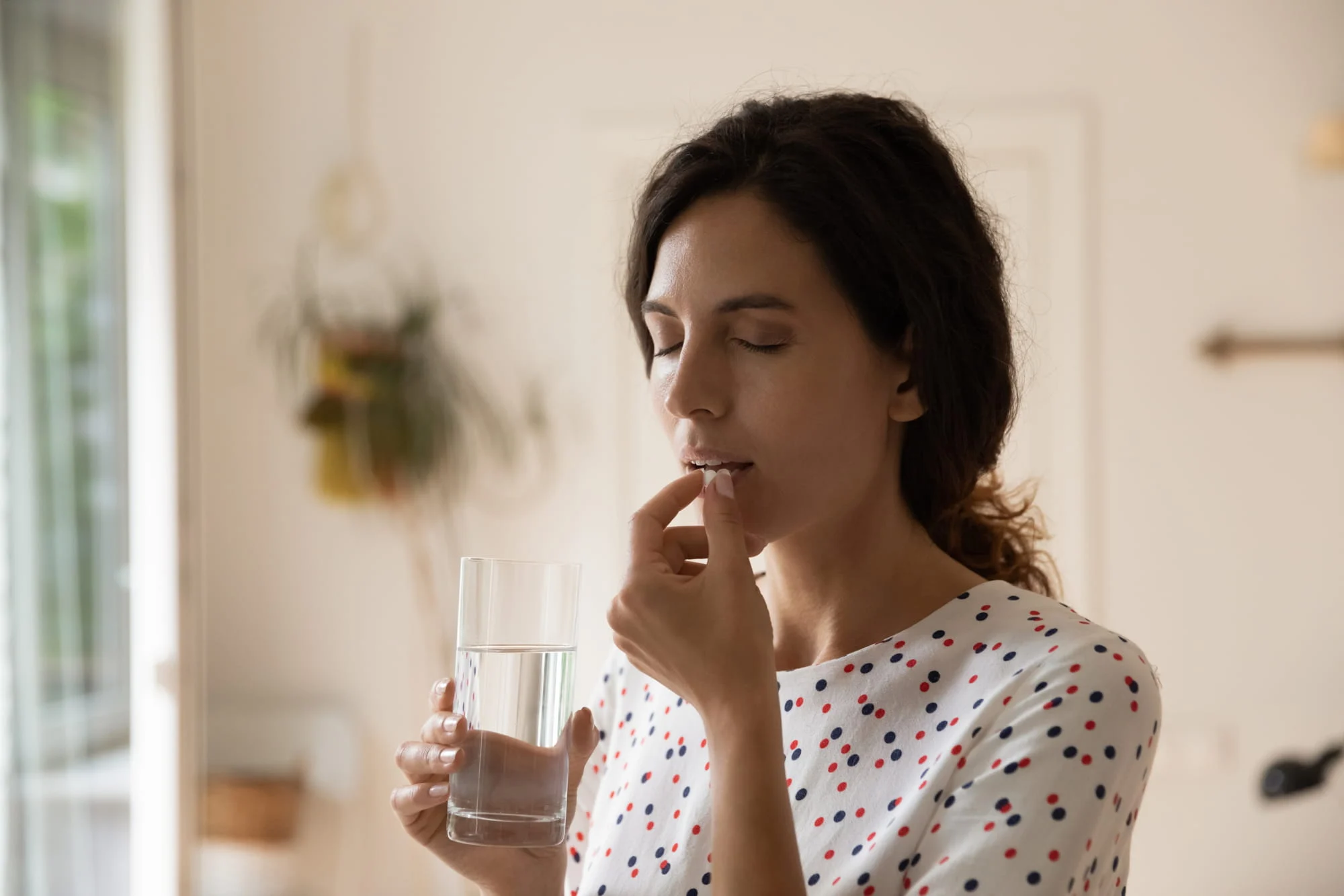 A woman taking medicines with water