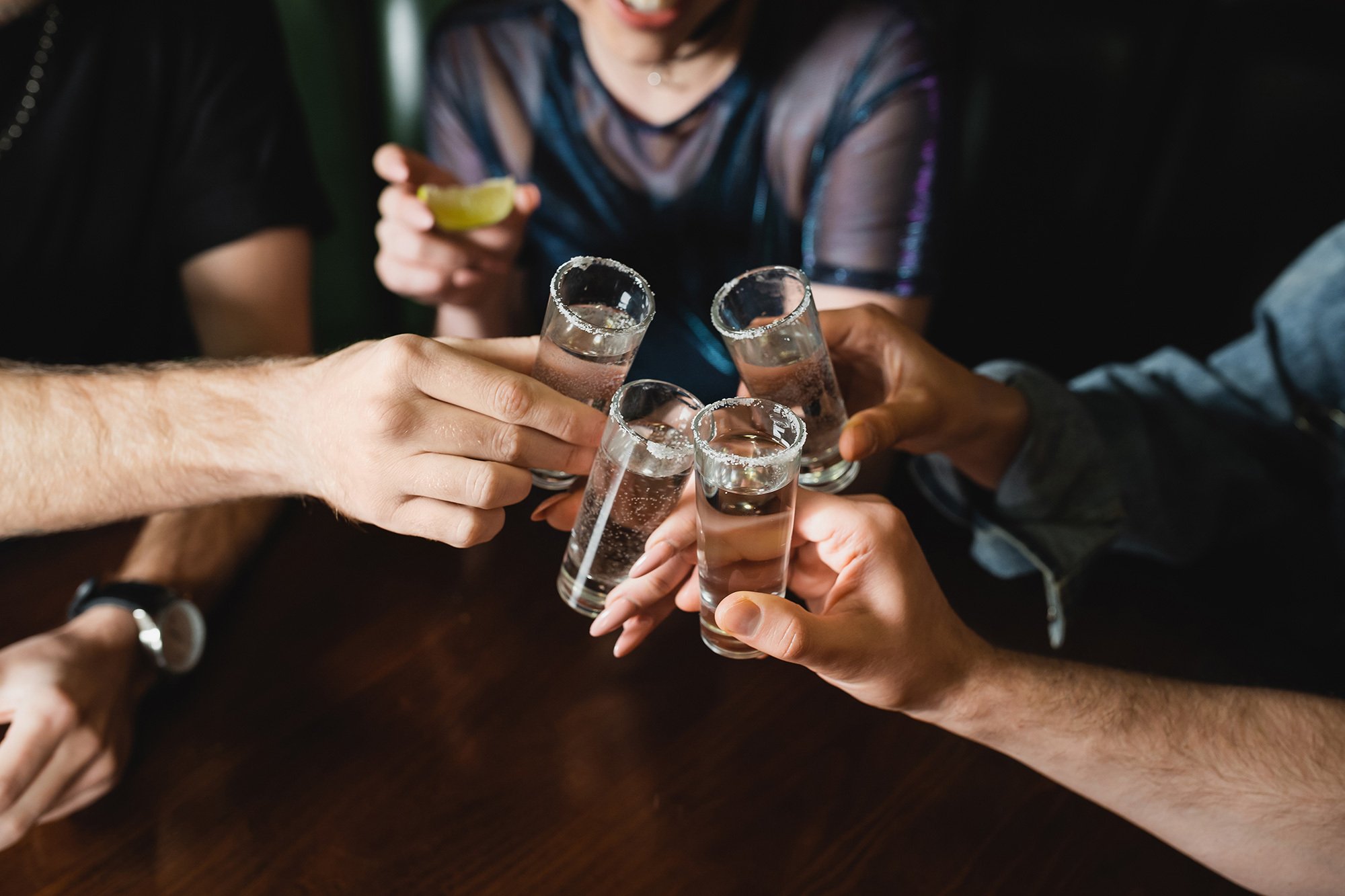 People holding glasses of tequila with salt.